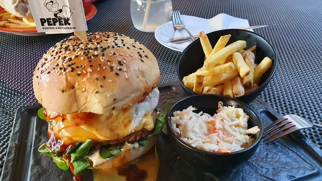 Burger s hranolkami a coleslawom na čiernom tanieri