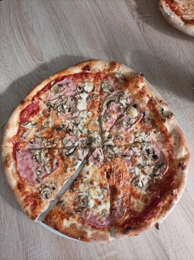 Pizza so šampiňónmi a salámou, nakrájaná na diely